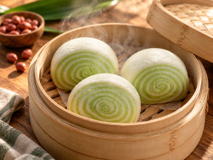 Pandan steamed buns in a bamboo steamer